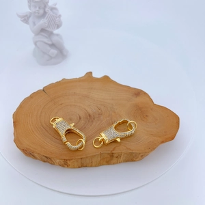 Close-up of gold lobster clasps with micro-pave cubic zirconia on wooden surface
