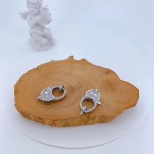 Detail of silver handcuff charms with micro-paved zircons on a wooden texture background