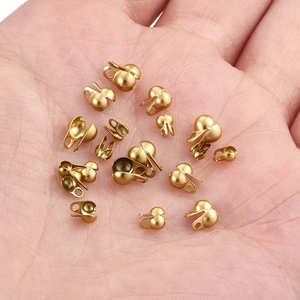 Macro detail of 18K gold-plated bead tips on a palm for DIY jewelry findings