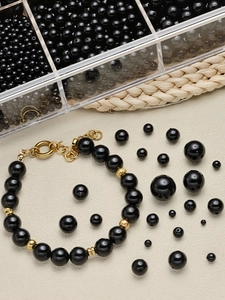Detail van gepolijste zwarte ABS-parels en gouden cilinders voor DIY-sieraden maken