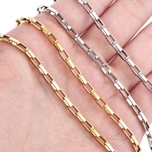 Close-up of gold and silver faceted rectangular link chains held in hand for scale