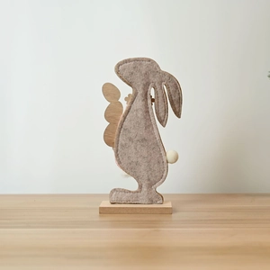 Detailed view of handmade gray felt Easter bunny with wooden base and white pompom tail