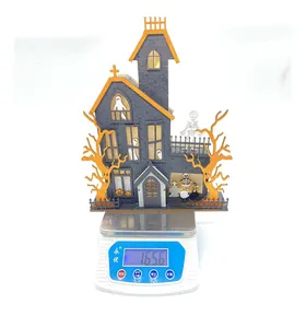Detailed view of 165.6g Halloween LED wooden house decoration on a digital scale