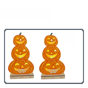Detail of stacked Halloween pumpkins with LED glowing faces and wooden base decor
