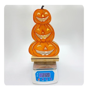Macro shot of Halloween wooden tiered pumpkin ghost decor being weighed on a digital scale