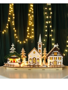 Close-up of LED glowing wooden Christmas village with miniature church and houses