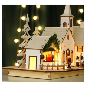Detail of wooden LED Christmas village scene with warm lights and snow-dusted finish