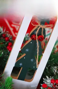 Detail of wooden Christmas sled ornament with green tree cutout and red bells