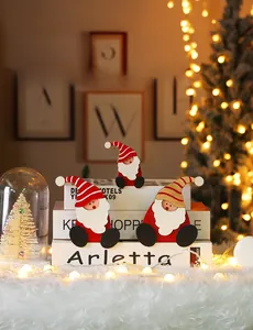 Detailed view of three small wooden Santa figurines on books with festive Christmas lights