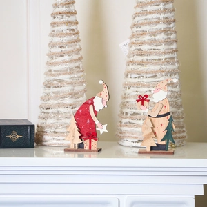 Detailed view of two handcrafted wooden Santa figurines with red ribbons and festive trees