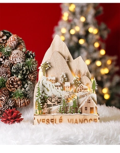Macro detail of wooden LED Christmas village scene with Santa and warm glowing lights