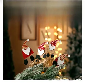 Detail of wooden Santa Claus trinkets with red hats placed in Christmas tree branches