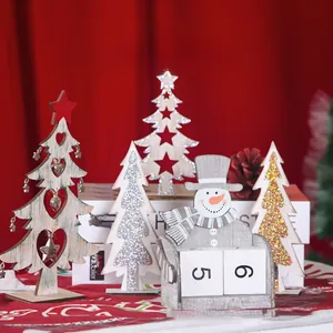 Close-up of wooden Christmas tree ornaments and snowman block calendar on red background
