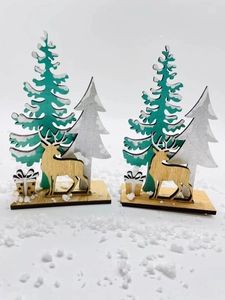 Close-up of laser-cut wooden Christmas tree and reindeer decor set with snowy base