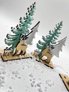 Detail of laser-cut wooden Christmas trees and reindeer figurines on a snowy base