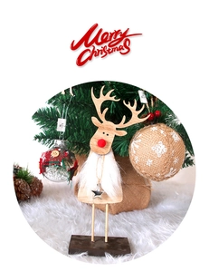 Detail of wooden Christmas reindeer decor with red nose and faux fur beard on soft white rug