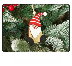 Detail of wooden Santa gnome ornament with striped hat hanging on a snowy Christmas tree