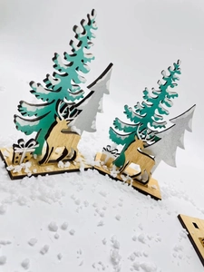 Detailed laser-cut wooden Christmas tree and reindeer figurines on artificial snow