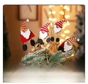Close-up of wooden Santa figurines with striped hats and burlap bows on Christmas tree