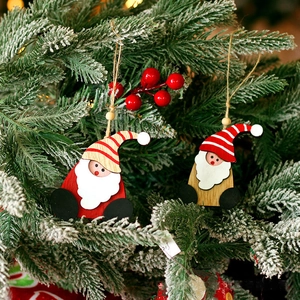Wooden Santa Claus tree ornaments with red hats and white beards on snowy branches