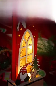 Close-up of a lit red wooden Christmas lantern with Santa Claus and a snowy tree