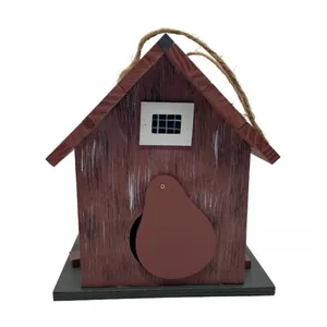 Close-up of a handmade wooden birdhouse with rustic red finish and hanging jute rope