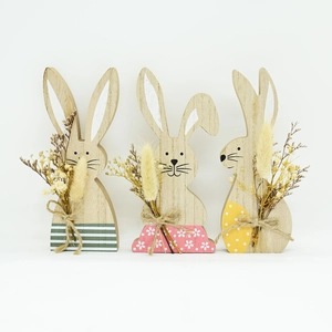Detailed close-up of three wooden Easter bunnies with dried flowers and jute twine bows