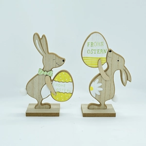 Close-up of wooden Easter bunnies with Frohe Ostern eggs and white pompom tails