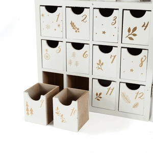 Detail of white wooden advent calendar with golden numbered drawers and festive illustrations