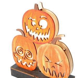 Detail showing stacked painted wooden pumpkins with laser-cut faces for Halloween decor