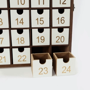 Detailed close-up of 24 white wooden advent calendar drawers with gold numbers