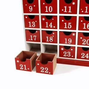 White wooden Christmas advent calendar house with 24 small red numbered storage drawers