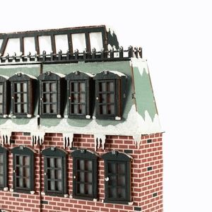 Lighted wooden Christmas house countdown calendar with red brick walls and snowy roof