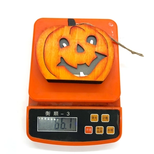 Detailaufnahme einer Halloween Kürbis Holzdeko mit einem Gewicht von 66,1g auf der Waage
