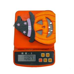 Close-up of a Halloween wooden pumpkin LED hanging ornament being weighed at 108.4g