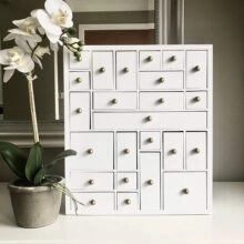 Detailed macro view of small white storage drawers with vintage metal knobs and orchid decor