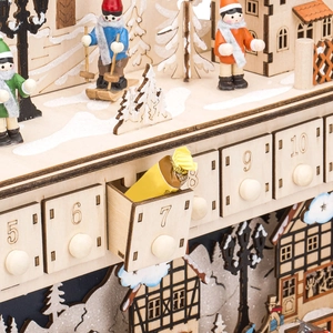 Macro detail of wooden advent calendar featuring mini village scenery and candy in open drawer