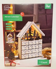 Detail view of wooden advent calendar with 24 small drawers and warm LED light forest scene
