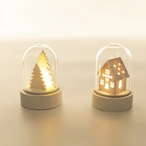 Close-up of LED wooden Christmas house and tree ornaments inside clear glass domes