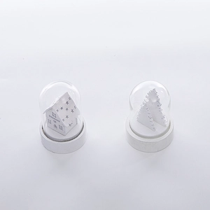 Close-up of dual glass dome ornaments featuring a white wooden house and Christmas tree