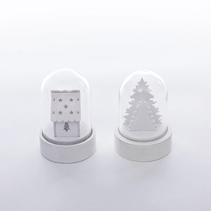 Detail of white miniature Christmas house and pine tree with cutout star patterns