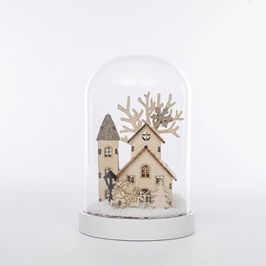 Vue détaillée d'un dôme en verre de Noël avec des cabanes en bois et de la neige factice
