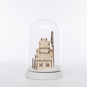 Détail d'une maison miniature en bois et paysage de neige sous un dôme de verre