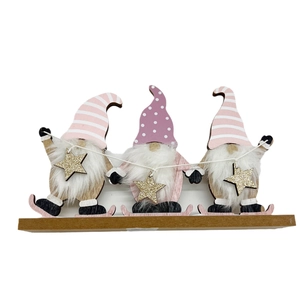 Trois gnomes de Noël en bois avec bonnets roses et skis fixés sur un socle en bois naturel