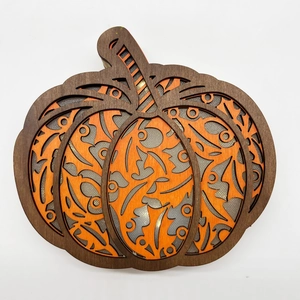 Detailed layered wooden pumpkin ornament with orange cutouts and sparkling silver background