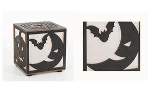 Close-up of laser-cut Halloween wood lantern with pumpkin and bat patterns