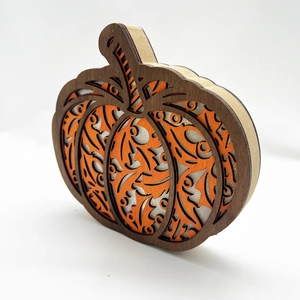 Macro detail of multi-layered wooden pumpkin LED ornament with laser-cut carving texture