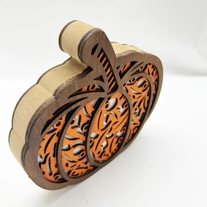 Detail of layered wooden pumpkin LED decor with intricate cutout harvest patterns