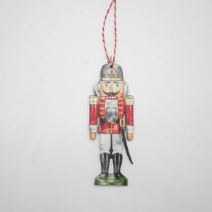 Close-up of wooden nutcracker soldier ornament with red uniform and striped cord