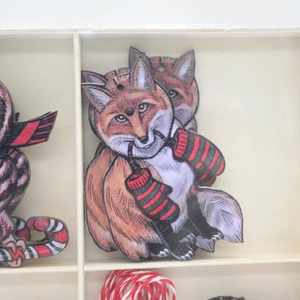 Detail of hand-painted wooden fox Christmas ornament with red winter scarf in a wooden box